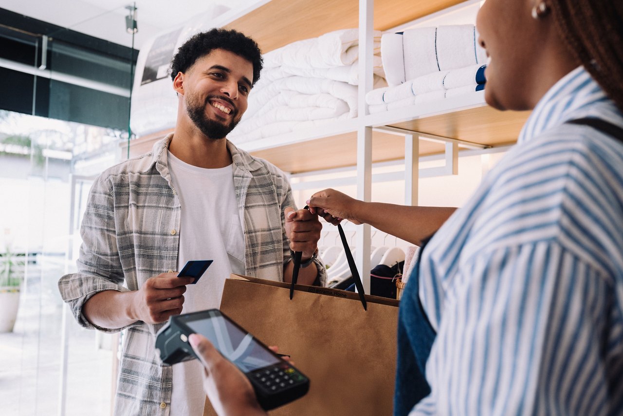 Saleswoman handing shopping bag to smiling customer after payment at the store